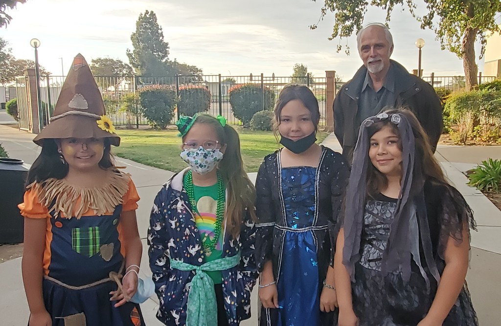 Four students in costumes with a teacher.